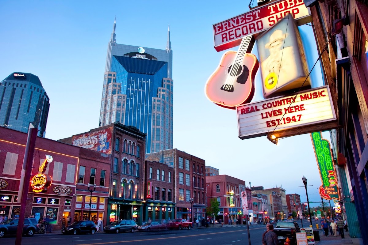 Lower Broadway in Nashville at dusk, neon signs lit along the honky-tonks
