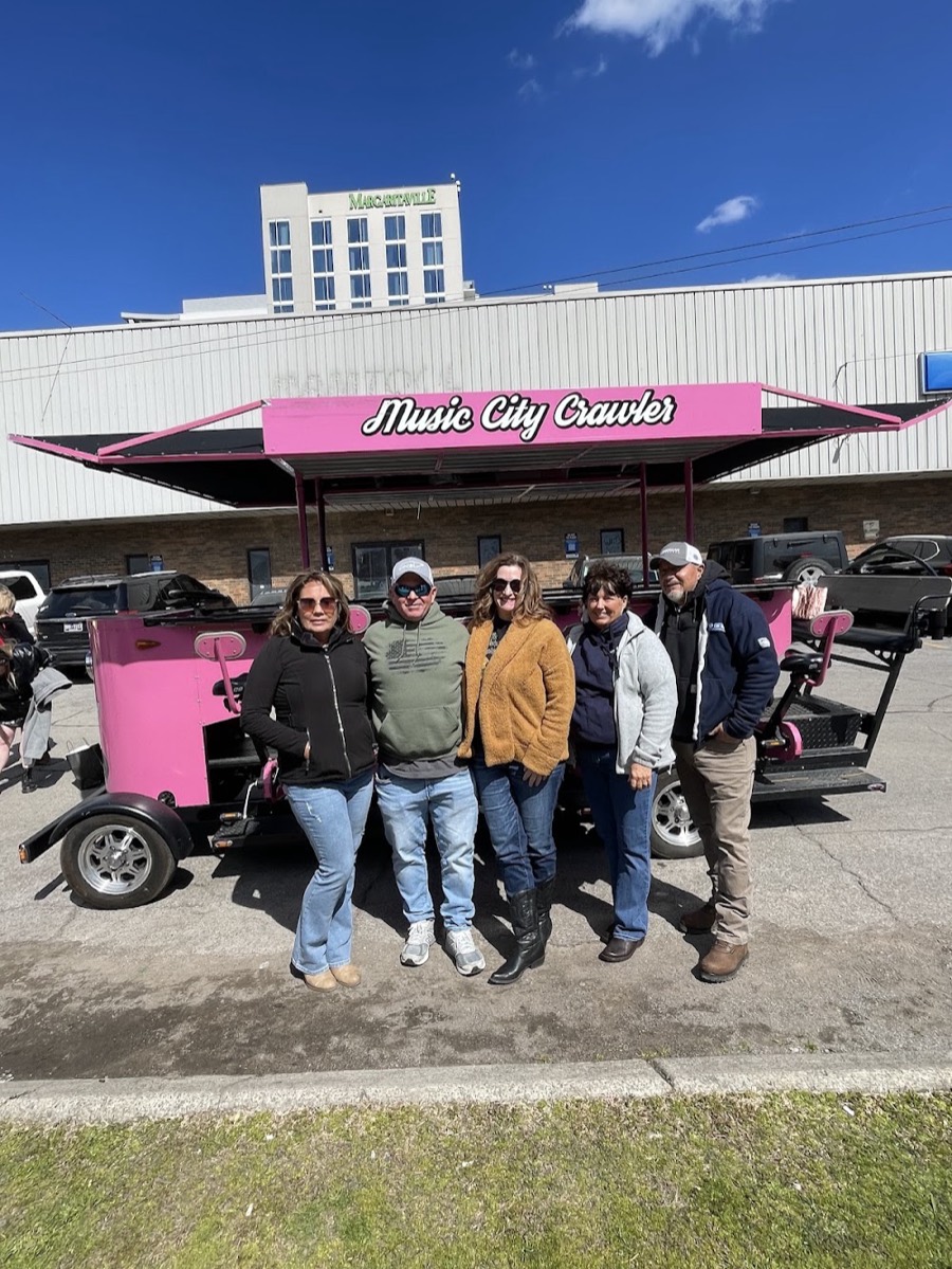 Five friends standing in front of the Music City Crawler beer bike in Nashville