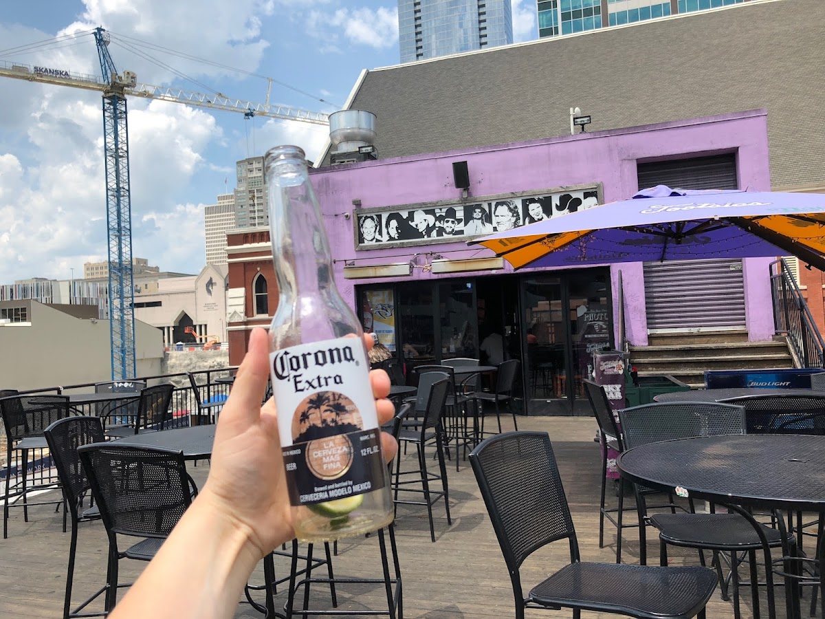 A cold beer held up on a Broadway rooftop in Nashville